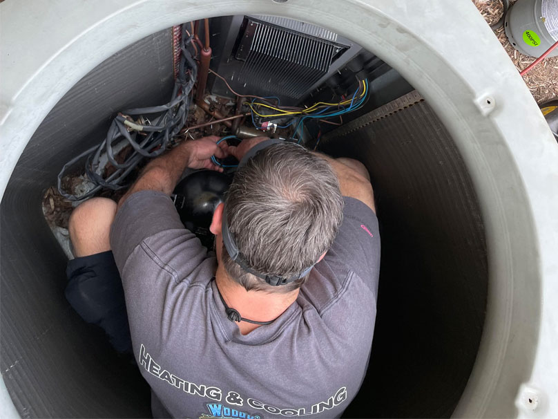 Woody technician working on air conditioner unit